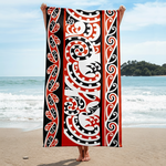 Person holding a Maori beach towel featuring symmetrical black and red Kōwhaiwhai rafter patterns.