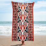 Full-length view of a white beach towel featuring a black and red Mangōpare Kōwhaiwhai pattern