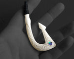 Hand carved Maori bone Hei Matau fish hook necklace with black adjustable cord shown in palm of hand
