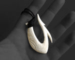 Hand-carved bone Hawaiian Makau fish hook necklace shown in the palm for size