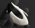 Detailed macro shot of the aggressive pointed barb on a hand-carved bone Hawaiian Makau hook pendant.