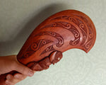 Hand-carved wooden Maori Patu club with intricate Koru engravings on a dark brown blade.