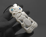 Detailed hand carving on a medium Maori bone Hei Tiki pendant showcasing traditional design