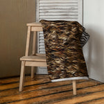 Māori Kahu Huruhuru Beach Towel draped over a wooden stool against a neutral wall.