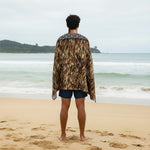 A full-length view of a beach towel featuring a photographic print of a Maori Kahu Huruhuru feather cloak.
