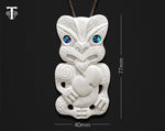 Close-up of hand-carved bone Hei Tiki showing Paua Shell inlay eyes and detailed engravings