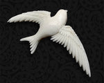 Close-up of the hand-carved cattle bone welcome swallow brooch showing intricate details