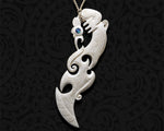 Close-up of a hand-carved Maori Manaia bone pendant with a Koru (spiral) design element