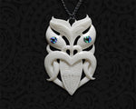 Hand-carved Maori Wheku bone pendant from Tuwharetoa Bone laid flat, showcasing the detailed ancestral warrior face and iridescent Paua shell eyes