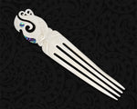 Hand-carved Maori heru from cattle bone featuring a stylised manaia and paua shell inlays